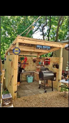 an outdoor bbq with grills and tables in the back ground, surrounded by trees