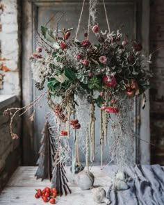 an arrangement of flowers hanging from the ceiling in front of a wooden table with other items