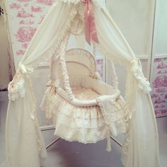 a white baby's cradle with pink bows on the top and canopy over it