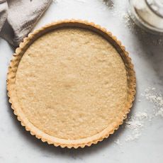 an uncooked pie crust sitting on top of a table next to some baking utensils