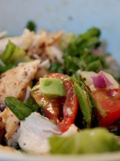 a white bowl filled with chicken, lettuce and tomatoes