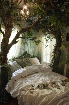 a bed with white sheets and pillows under a tree