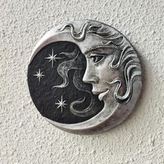 a metal plaque with a woman's face and stars in the sky above it