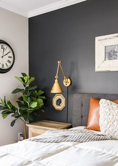 a bedroom with a bed, nightstand and clock on the wall next to it's headboard