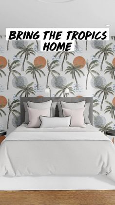 a bed with white sheets and pillows in front of a palm tree wallpaper