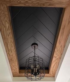 a chandelier hanging from the ceiling in a room with wood paneling on the walls