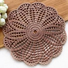 crocheted doily on a cutting board next to flowers