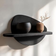 two black vases are sitting on a shelf