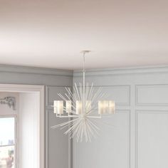 a chandelier hanging from the ceiling in a room with white walls and furniture