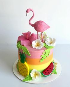 a cake decorated with pink flamingo, watermelon and flowers