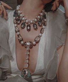 a woman in a white dress wearing a necklace with pearls and jewels on her neck