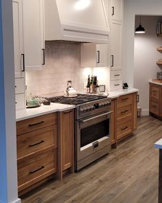 a kitchen with white cabinets and wood flooring is pictured in this image, there are lights on above the stove