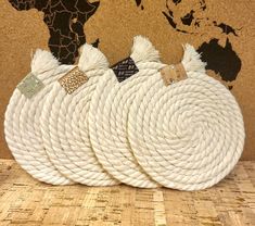 three white rope bags sitting on top of a wooden table next to a world map