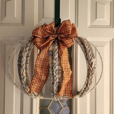 a wreath hanging from the front door with a bow on it's headband