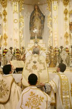 the priest is standing in front of the altar with two other priests at his side