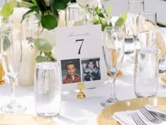 the table is set with wine glasses, plates and silverware