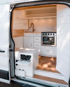 the interior of a small white van with its door open to reveal an oven and stove