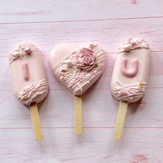 three heart shaped lollipops with pink frosting on them sitting next to each other