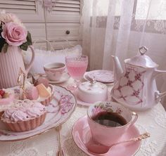 a table topped with pink cupcakes and tea cups