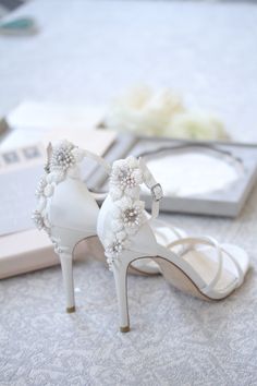 a pair of white high heeled shoes sitting on top of a table next to a book