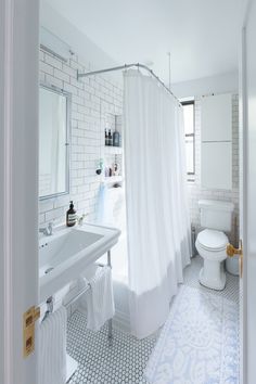 a bathroom with a white shower curtain next to a toilet and sink under a mirror