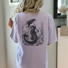 "Get ready to show your style with our back printed Vintage Mermaid T-Shirt! Perfect for a beach party, concert or or just a casual day out, this graphic tee is a must-have.  Proudly Printed on Comfort Colors® tees, for that insanely soft, vintage look and feel.  Without doubt, this will be your favorite shirt. With its vintage-inspired design, this shirt is perfect for those who love a boho, western, or retro look. The oversized fit and soft, comfortable fabric make it the perfect choice for a day on the ranch or a night out on the town. Made from garment-dyed fabric, this shirt has a unique, weathered look that will only get better with time. This cute shirt is perfect for any occasion. ⇒ PRODUCT DETAILS 100% ring-spun cotton 7/8\" double-needle topstitched collar Double-needle armhole, Mermaid Shirts, Mermaid Tshirt, Mermaid Top, Mermaid Shirt, Vintage Mermaid, Comfort Colors Tee, Mermaid Birthday, Vintage Inspired Design, Feminine Look