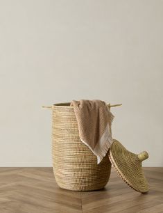 a basket with a towel hanging from it on a wooden floor next to a wall