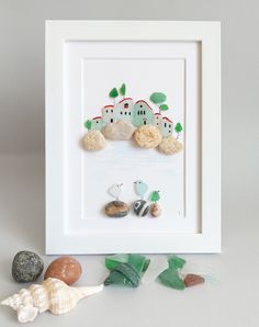 a white frame with some shells and sea glass on it next to a seashell