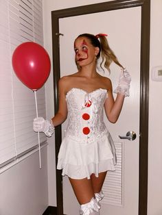 a woman dressed as a clown holding a red balloon