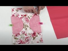 someone is cutting fabric with scissors on top of a piece of paper and pink material