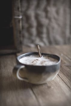 there is a cup of coffee on the table with a cinnamon stick sticking out of it