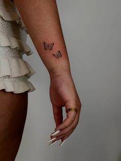 a woman's hand with a butterfly tattoo on her left wrist and the other arm