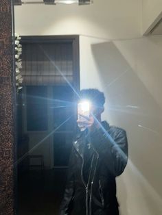 a man taking a selfie in front of a mirror with the light shining on him