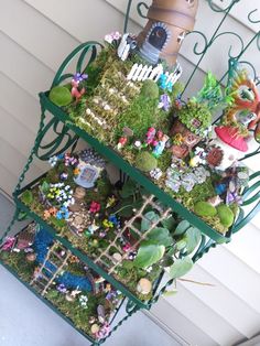 a three tiered shelf filled with lots of plants and small figurines sitting on top of it