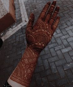 a person's hand with hennap on it and brick walkway in the background