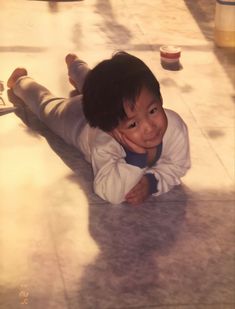 a little boy laying on the ground with his arms and legs spread out in front of him