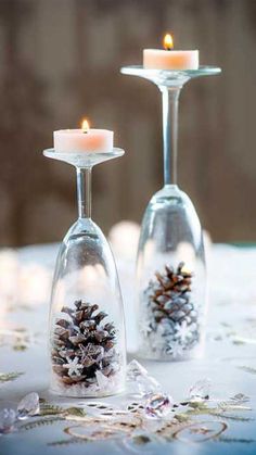 two wine glasses with pine cones in them are sitting on a table next to each other