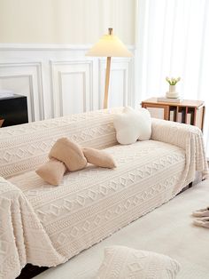 a living room with a couch covered in a blanket and two pillows on the floor