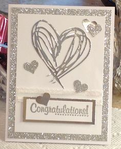 a white card with silver foil hearts and congratulations written on the front, along with other cards