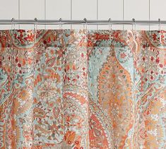 a shower curtain with an orange and blue paisley pattern on the outside, hanging from a metal rod