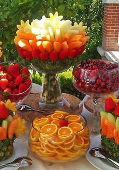 a table topped with lots of fruit and veggies on top of glass dishes