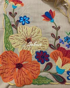 an embroidered flower design is shown on the side of a white cloth with orange, blue and red flowers