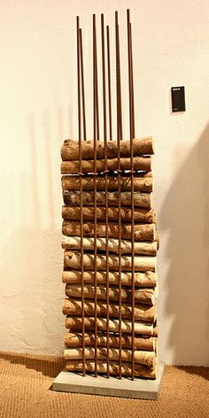 a stack of sticks sitting on top of a wooden floor next to a white wall