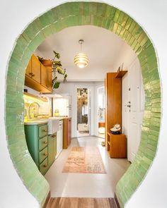 an oval view of a kitchen with green and white tiles on the walls, along with hardwood floors