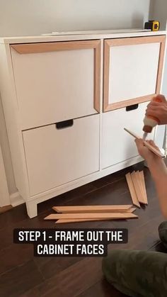 a person kneeling down on the floor with some wood in front of them and an unfinished cabinet