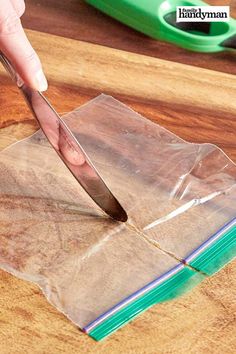 a person cutting up some paper with a large knife on top of it and a green object in the background