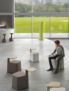 a man sitting on top of a white bench in a room filled with tables and stools