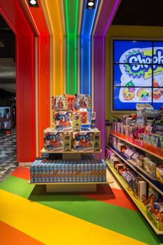 the inside of a toy store with rainbow colored walls and shelves filled with various toys