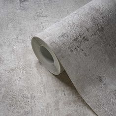 a roll of grey colored carpeting next to a white wall with a gray tape on it