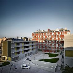 an apartment complex with cars parked in the parking lot next to it and buildings on either side